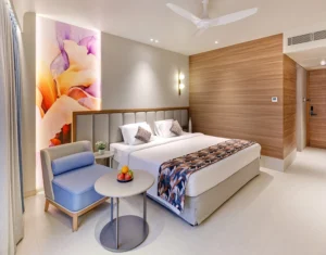 Hotel Tunga Regale spacious luxury room in Andheri East, Mumbai, featuring a king-size bed, soft ambient lighting, wood-paneled walls, contemporary furnishings, and a large floral mural.