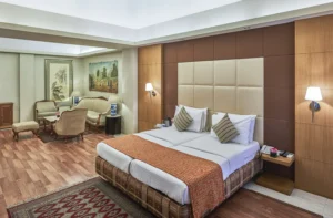 Hotel Astoria spacious suite in Mumbai with twin beds, modern decor, soft lighting, comfortable seating area, wooden flooring, and elegant furnishings.