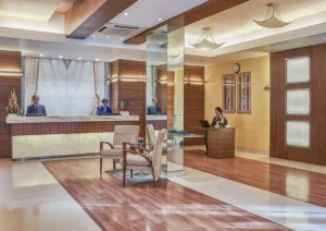 Hotel Astoria lobby in Mumbai with polished marble and wood interiors, reception desks, welcoming staff, comfortable seating, and bright ambient lighting.