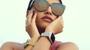 Woman’s wrists wearing a gold luxury watch with diamond accents and a silver smart watch with a metallic strap, hands gracefully posed against a light background.