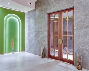 Hotel Tunga Regale modern banquet hall entrance with tall decorative glass doors, soft green accent wall, elegant marble flooring, and stylish contemporary decor in Andheri East, Mumbai.