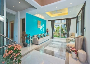 Sajala spacious luxury living room with bright teal accent wall, plush seating, large windows, indoor plants, and modern decor.