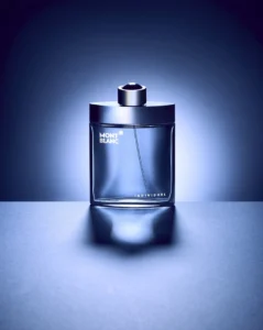 Montblanc Individuel perfume bottle with silver cap, transparent glass, and blue lighting on a dramatic background.