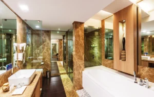 Hotel GCC luxury bathroom with marble finishes, glass shower, soaking bathtub, spacious vanity, and contemporary decor in Mumbai.