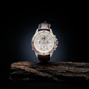 "Luxury men's chronograph wristwatch with white dial, silver case, and brown leather strap displayed on rustic wood against a black background".